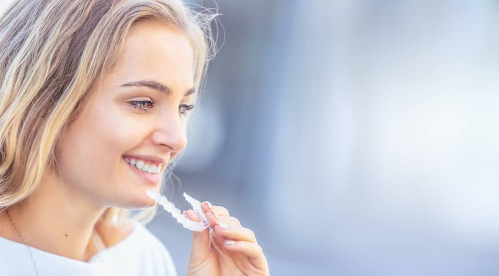 Invisalign orthodontics concept - Young attractive woman holding — Photo